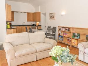 a living room with a couch and a kitchen at Hen Stabl in Beaumaris