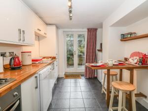 uma cozinha com armários brancos e uma mesa e cadeiras em The Garden Flat em Buxton