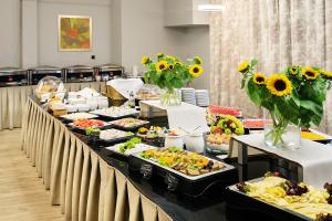 a buffet line with a lot of food and sunflowers at Golden Tulip Krakow City Center in Kraków