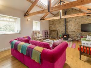 a living room with a pink couch and a fireplace at The Cowshed in Horsley