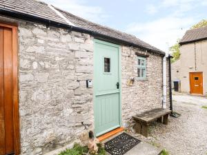 a stone cottage with a green door and a bench at The Studio in Bradwell +3 photos