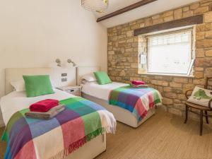 a bedroom with two beds and a stone wall at The Cowshed in Horsley