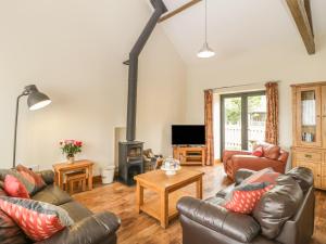 a living room with leather furniture and a wood stove at The Old Cart Shed in Blandford Forum