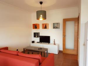 a living room with a red couch and a television at Cozy apartment in Algarve West Coast - Aljezur (2 min da Praia Monte Clérigo) in Aljezur