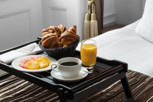 a breakfast tray with a cup of coffee and croissants and orange juice at Phoenix Copenhagen in Copenhagen