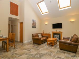 sala de estar con muebles de cuero y TV en Apple Tree Cottage, en Dunnington