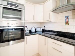 a kitchen with white cabinets and a stove top oven at The Moorings in Conwy