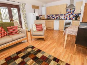 a kitchen with a couch and chairs and a table at Dairy Cottage in Llanrwst