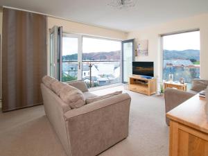 a living room with a couch and a tv and windows at The Moorings in Conwy