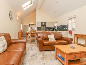 a living room with brown leather furniture and a kitchen at Pear Tree Cottage in York