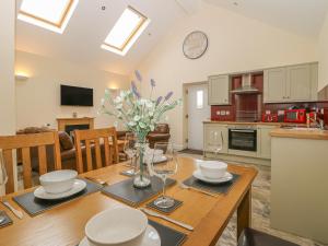 cocina y sala de estar con mesa de madera y jarrón de flores en Apple Tree Cottage, en Dunnington