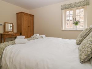 Un dormitorio con una cama blanca con toallas. en Apple Tree Cottage, en Dunnington