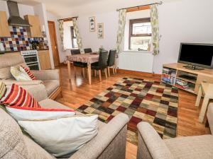 a living room with a couch and a tv and a table at Dairy Cottage in Llanrwst