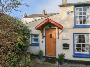 a white house with a brown door and blue windows at The Retreat in Bideford