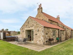 a stone house with a patio and a grill at Orchard Cottage in Durham