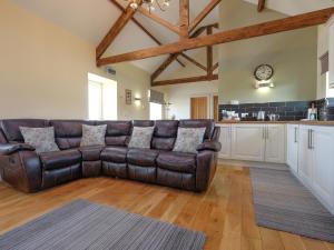 a leather couch in a living room with a kitchen at Fern Cottage in Copley