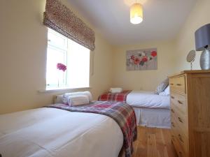 two beds in a small bedroom with a window at Fern Cottage in Copley