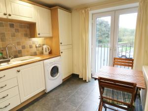 a kitchen with a washing machine and a table with chairs at Kingfisher Barn in Kendal