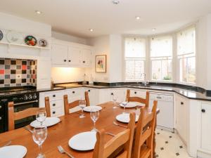 a kitchen with a wooden table and chairs and a kitchen with white cabinets at Eden House in Penrith