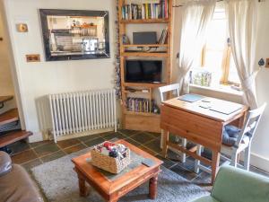 sala de estar con mesa, escritorio y TV en The Old Stable en Abergavenny