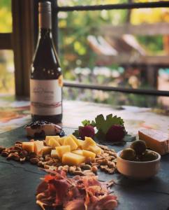 a bottle of wine and a bunch of cheese and grapes at Hotel Hoja de Parra in Santa Cruz