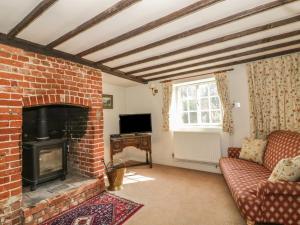 a living room with a brick fireplace and a tv at Woodlands in Eye