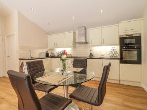 a kitchen with a glass table and chairs at Rose Cottage in Belper