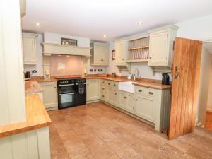 a kitchen with white cabinets and a tile floor at The Old Stables in Chesterfield