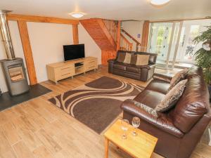 uma sala de estar com um sofá de couro e uma televisão em Kingfisher em Whitland