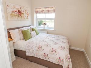 a bedroom with a bed with a pink floral bedspread at The Byre in Ashbourne