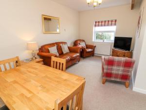 a living room with a table and chairs and a television at The Byre in Ashbourne