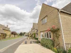 a brick house with flowers on the side of a street at Rosemary Cottage in Bourton on the Water