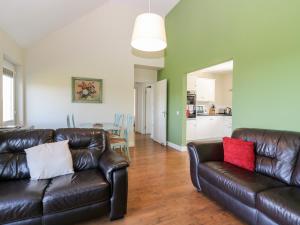 a living room with two leather couches and a kitchen at Driftwood Cottage in Craignure