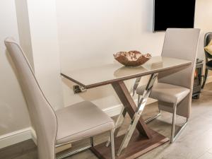 a glass table with two chairs and a bowl on it at Ash Cottage in Bakewell