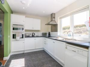 a kitchen with white cabinets and a window at Sunset Cottage in Salen