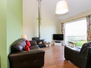 uma sala de estar com um sofá de couro e uma lareira em Driftwood Cottage em Craignure