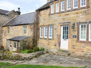 an old stone house with a white door at Ash Cottage in Bakewell