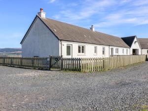 une maison blanche avec une clôture devant elle dans l'établissement Driftwood Cottage, à Craignure