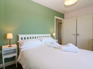 a bedroom with a white bed and a green wall at Sunset Cottage in Salen