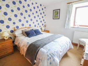 a bedroom with a bed with a blue patterned wall at Woodlands in Halton West