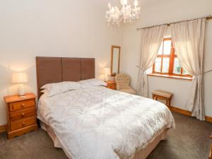 a bedroom with a large bed and a chandelier at Dove Cottage in Brampton