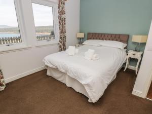 a bedroom with a large white bed with two pillows at Starfish Cottage in Craignure