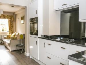 une cuisine avec des armoires blanches et des comptoirs noirs dans l'établissement Ash Cottage, à Bakewell