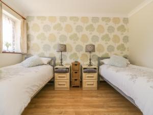 two twin beds in a room with two tables at Kingfisher in Wattisfield