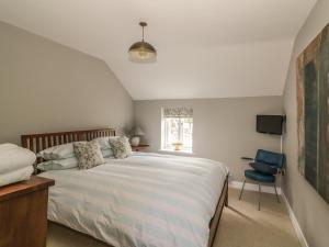 a bedroom with a large bed and a blue chair at Mulberry Cottage in Hadleigh