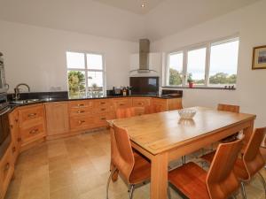 a kitchen with a wooden table and some windows at The Hide in Greyabbey