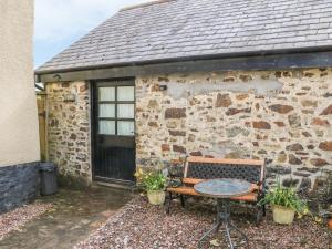 a table and a bench in front of a stone building at The Old Workshop in Knowstone