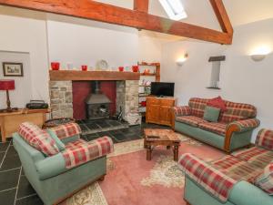 a living room with two couches and a fireplace at Beudy Bach in Llanddeiniolen