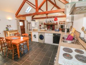 a kitchen with a wooden table and a dining room at Beudy Bach in Llanddeiniolen