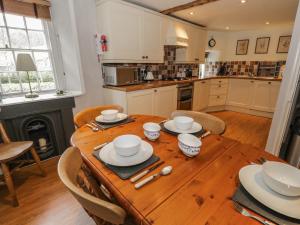 una cocina con una mesa de madera con platos. en Rowan Cottage, en Grasmere